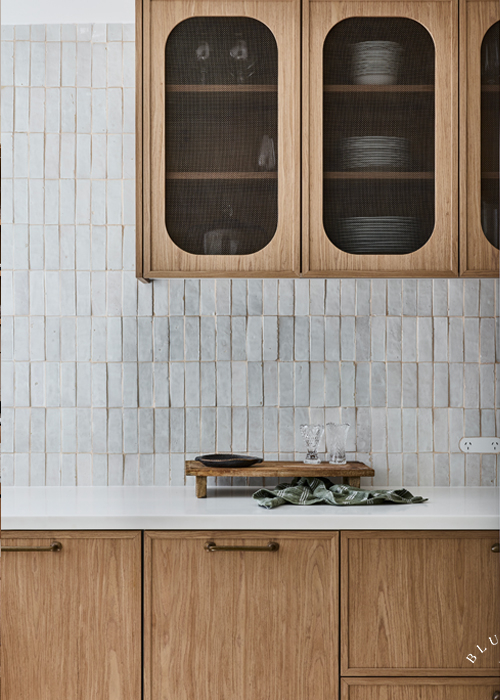 A slim line shaker doors with curved frames and aged brass mesh upper cabinetry.