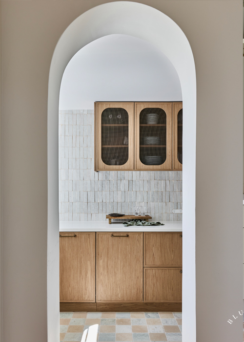 Curved entry way to the butlers pantry featuring textural tiled walls and timber detailed cabinetry.